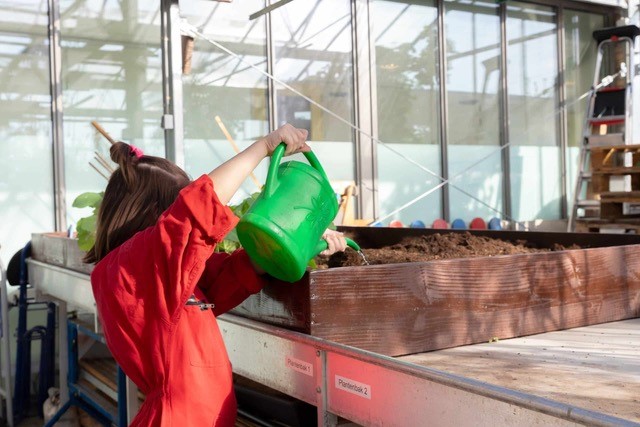 Kind met gieter bij moestuin