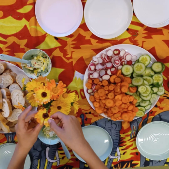 Een bord met wortel, radijs en komkommer op een kleurrijk tafelkleed